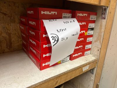 une pile de boîtes rouges posée sur une étagère, sur laquelle est accrochée une pancarte