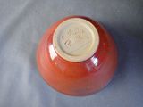 a red vase with a brown lid on a table