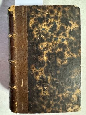 un vieux livre posé sur une table à côté d'un mur blanc