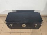 an old black suitcase sitting on a tiled floor next to a wall