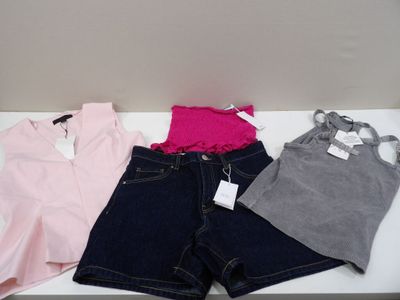 three pairs of shorts and a pink top are on a white table