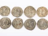 six silver coins of different sizes and shapes on a white surface
