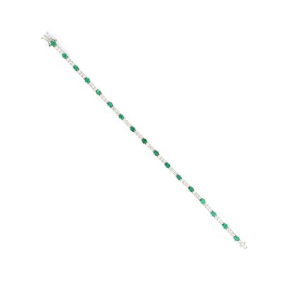 un gros plan d'un bracelet orné de pierres vertes sur fond blanc