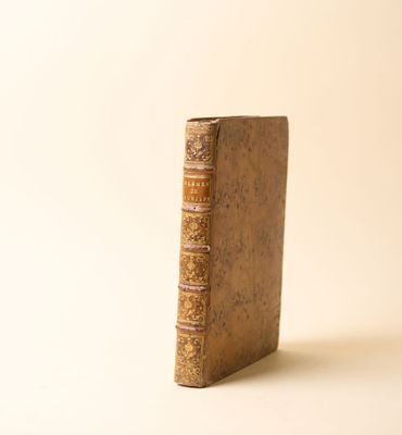 un vieux livre posé sur une table à côté d'un mur blanc