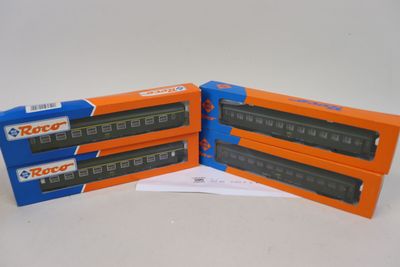 trois boîtes contenant des trains miniatures, posées sur une surface blanche
