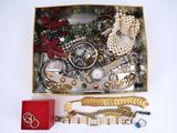 une boîte remplie de bijoux posée sur une table, à côté d'une boîte rouge