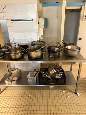 de nombreuses casseroles et poêles posées sur une table en acier inoxydable