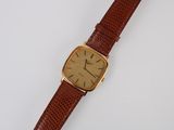 a close up of a watch on a white surface with a brown strap