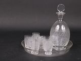 une carafe en verre et quatre verres posés sur un plateau