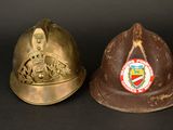 pair of antique fire helmets on a black background with a coat of arms in the center