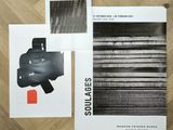 three black and white posters on a wooden floor with a red object