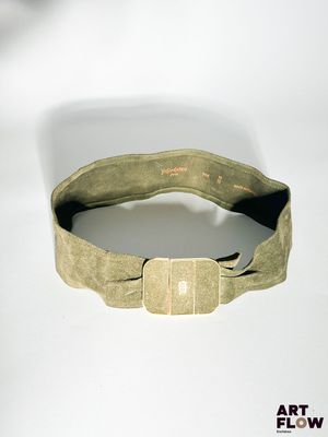 une ceinture munie d'une boucle métallique, posée sur une surface blanche