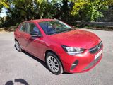 the red car is parked in the parking lot next to the trees