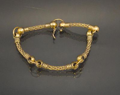 a gold bracelet with a knot and beads on a black surface