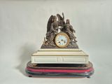 une statue d'un ange tenant une horloge posée sur une table