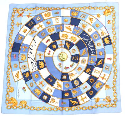 a close up of a blue and white square scarf with gold chains