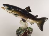 figurine représentant un poisson posé sur un rocher, sur fond blanc