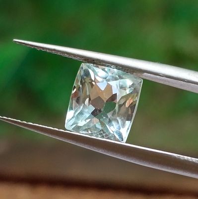 someone is holding a pair of pliers with a light blue diamond in it