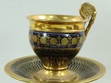 a blue and gold cup and saucer on a plate