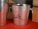 a silver bucket and a silver cup on a red table