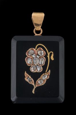 un gros plan d'un pendentif noir et doré orné d'une fleur