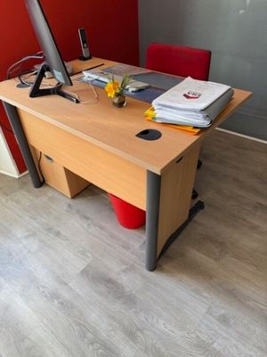 a desk with a computer and a red chair in the corner
