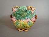 a green vase with flowers on it on a gray surface