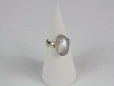 bague en argent avec une pierre blanche sur un cône blanc, sur fond blanc