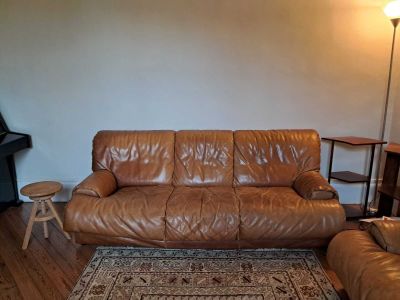 un canapé en cuir marron dans un salon où se trouve un tapis au sol