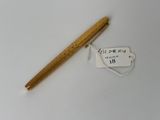 un stylo en bois et une étiquette sur une surface blanche