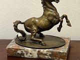 bronze statue of a horse on a marble base on a table