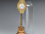 une horloge posée sur une table, sous une cloche en verre