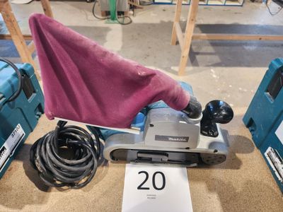 une ponceuse recouverte d'une serviette rose, posée à côté d'autres outils