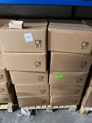 des cartons empilés sur des palettes dans un entrepôt, avec un mur bleu en arrière-plan