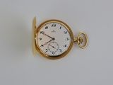 une montre de poche en or sur une surface blanche