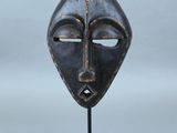 image d'un masque en bois sur un support sur fond blanc