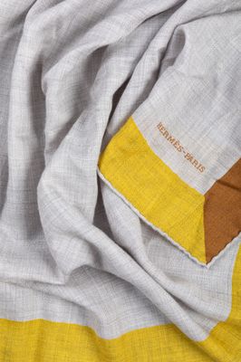 a close up of a yellow and grey scarf on a bed