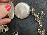 a person holding a silver pocket watch with a chain around it