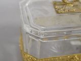 a small glass box with a gold decoration on it