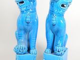 pair of blue foo foo foo statues on pedestals against a white background