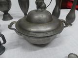 a silver pot with a lid on a table next to other silver vases