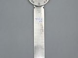 a silver spoon with a clock on it on a gray surface