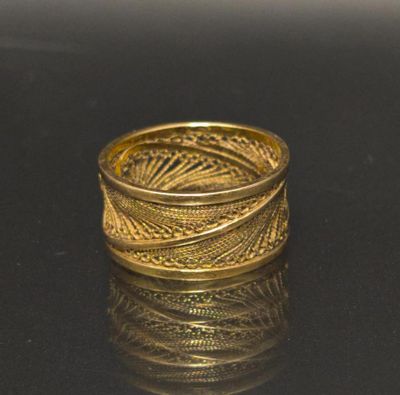a gold ring that is sitting on a black surface