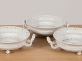 three white porcelain bowls with handles and handles on a wooden table