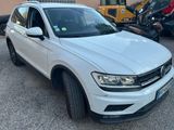 a white volkswagen tigua parked in a parking lot next to other cars