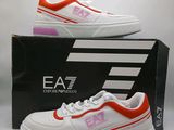 une image représentant une paire de baskets blanches et orange posées sur une boîte