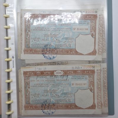 deux vieux billets de banque rangés dans un classeur posé sur une table