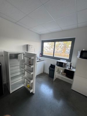 Quelqu'un prend une photo d'une cuisine vide où se trouve un réfrigérateur