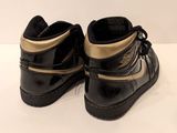 black and gold high top sneakers on a white surface