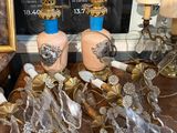 de nombreux vases en verre posés sur une table, avec un tableau en arrière-plan